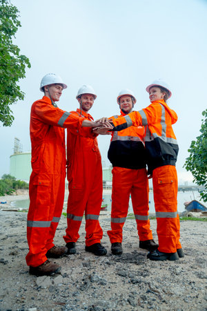 Vertical image of group petrochemical workers or technicians stand and hold hands together in front of factory tank.の写真素材