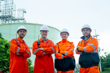 Group of petrochemical workers men and woman or technicians stand with arm-crossed also look at...