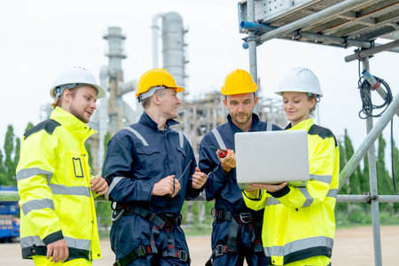 Group of petrochemical workers or technicians work together with one hold laptop and they stand in front the factory.の写真素材