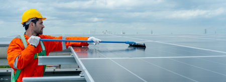Wide shot of profession engineer or technician worker use cleaning brush to clean solar cell panel in area of rooftop of building.の写真素材