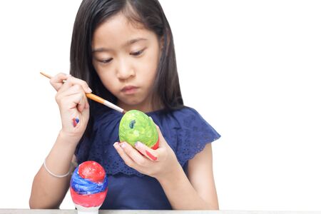 Little girl is painting eggs preparing for Easterの写真素材