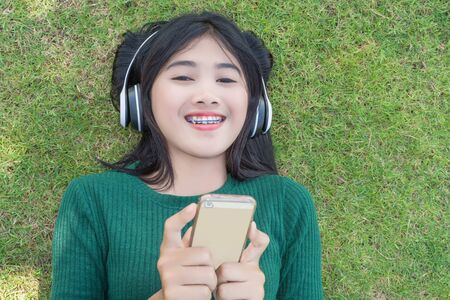 Young beautiful woman girl listening music headphones outdoorの写真素材