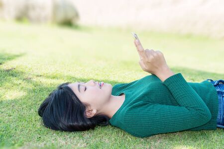 womwen girl lying on the lawn with smartphoneの写真素材