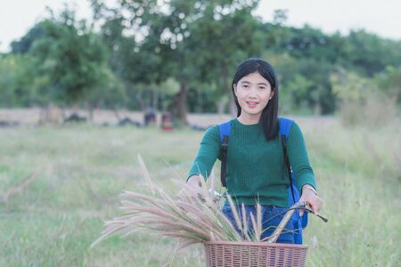 Teenager girl, bicycle with flowers basket in outdoor landscapeの写真素材