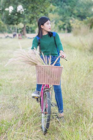 Teenager girl, bicycle with flowers basket in outdoor landscapeの写真素材