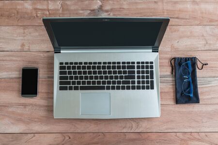 Laptop, glasses blue and smartphone on wood top viewの写真素材