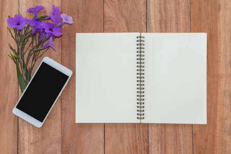 top view notebook, smartphone and flower on wooden table.
