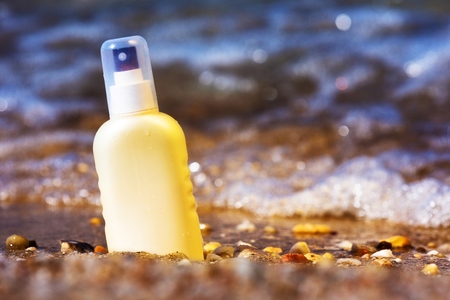 Sun cream bottle in the shallow sea water の写真素材