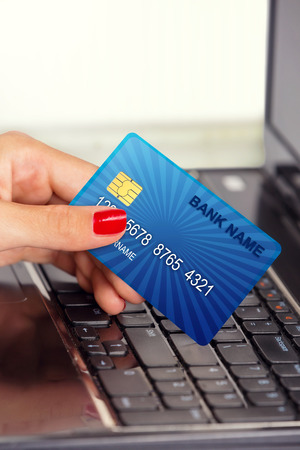 Close up of a female hand holding credit card, in front of laptop keyboard の写真素材
