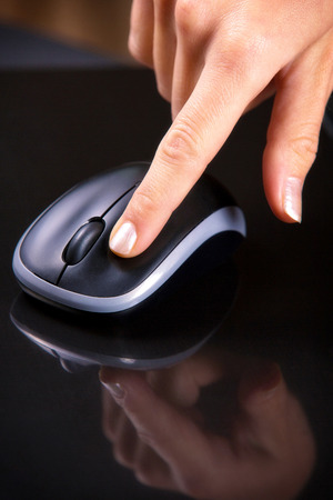 Female hand clicking computer mouse の写真素材