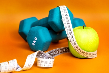 Fitness composition with dumbbells and green apple in foreground.の写真素材