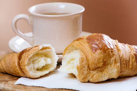 Fresh croissant and cup of tea, on kitchen table.の写真素材