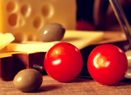 Sliced yellow cheese and couple of cherry tomatoes.の写真素材