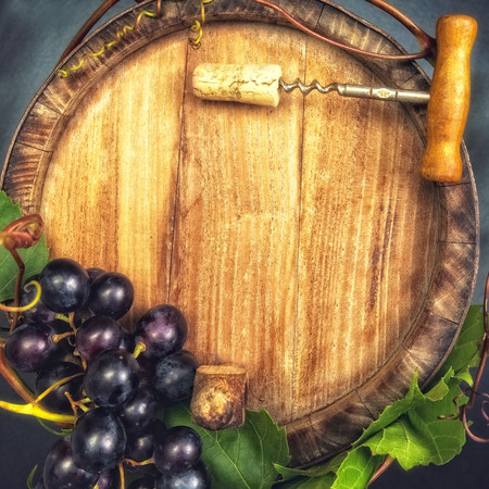 Top view of the old wooden barrel, with dark blue grapes and bottle opener on it.の写真素材