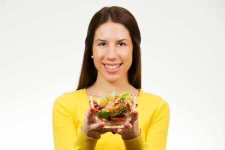 Beautiful young woman, holding bowl of salad and smiling, isolated on white background.の写真素材