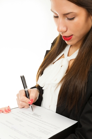 Portrait of a young female manager, signing document, isolated on white background.の写真素材