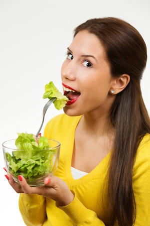 Beautiful young woman, eating lettuce, isolated on white background.の写真素材
