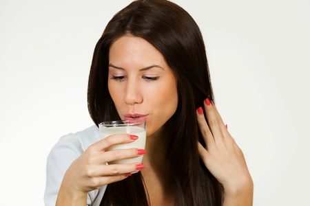 Beautiful young woman drinking milk, isolated on white background.の写真素材
