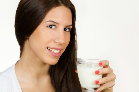 Beautiful young woman drinking milk, isolated on white background.の写真素材