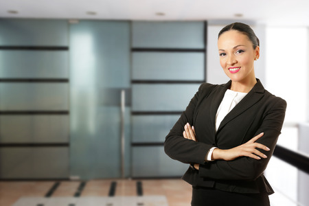 Business dressed woman in hands crossed, smiling in front of the office.の写真素材