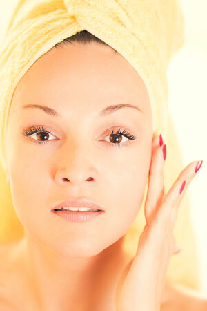 Beautiful young woman gently touching her faceの写真素材