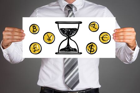 Time is money concept.Business man holding paper with drawings of different currencies coins and sand clock.の写真素材
