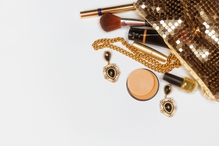 Golden woman accessories. Make up pieces, jewelry and shiny purse. Top view.の写真素材
