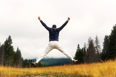 Male adventurist jumping on top of the hill.の写真素材