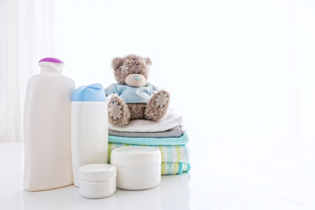 Several cosmetics product for children next to towels and teddy bear.の写真素材
