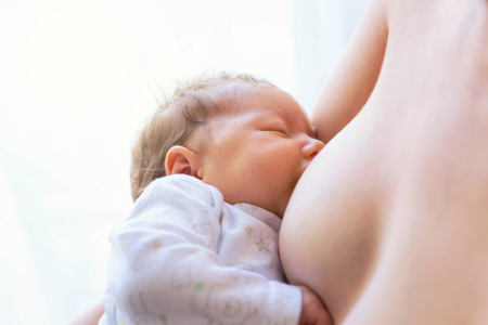 Young mother breastfeeding newborn baby.の写真素材