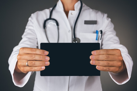Young female doctor showing tablet with empty space for massage.の写真素材