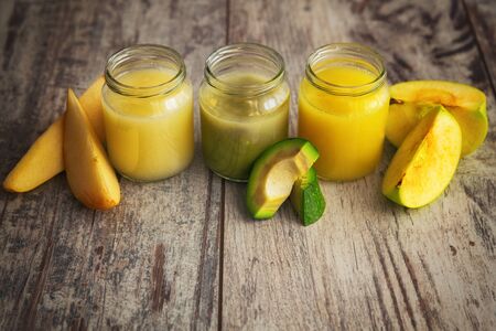 Homemade baby food in jars, next to raw vegetables.の写真素材