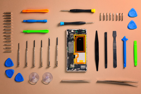 Smartphone cover removed, internals exposed with tools arranged around.の写真素材