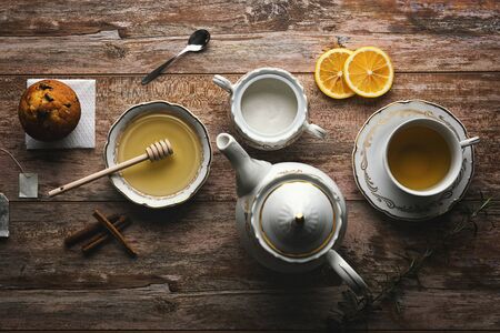 Beautiful arranged tea set up. White ceramic tea dishes next to tea ingredients , on op of the wooden table.の写真素材