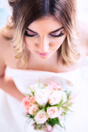 Romantic wedding moments. Portrait of a beautiful young bride holding flower bouquet. Top view.の写真素材