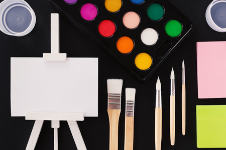 Lovely artistic concept. Colorful watercolor  palette, new wooden brushes, sticky notes and small...