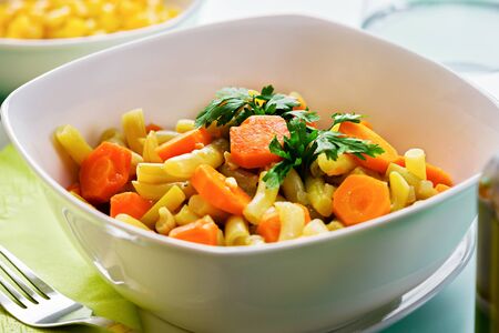 Served plate of mixed vegetarian lunch. Close up of green beans, carrots and spices.の写真素材