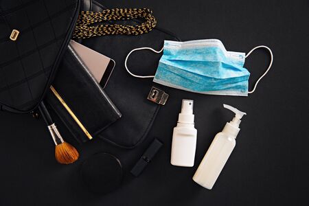 Top view of women purse, with protective face mask and hand sanitizer inside it.の写真素材