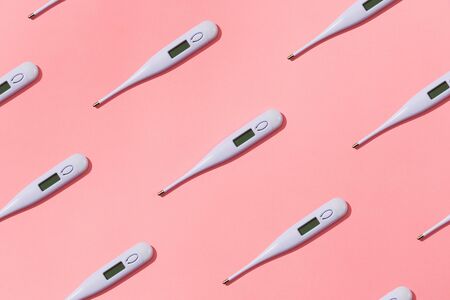 Digital thermometers isolated against pink background.
