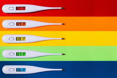 Top view of digital thermometers displaying rise in body temperature, isolated on colorful background.の写真素材