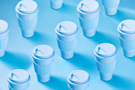 Blue paper cups laid out in repetitive pattern on top of blue background.の写真素材