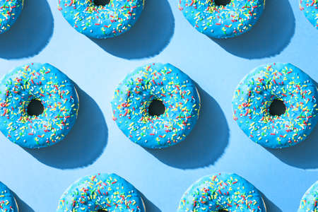 Blue donuts flat lay pattern, on top of blue background with hard shadow.の写真素材