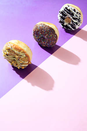 Colorful donuts flat lay on top of multi-color background, with hard shadow and copy space .の写真素材