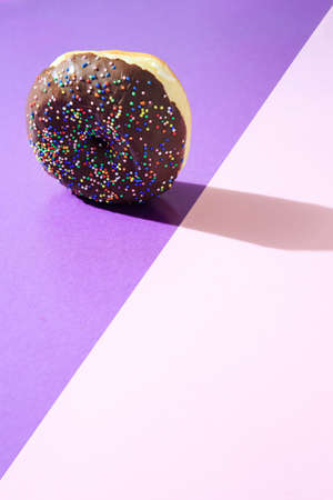 Donut with chocolate icing, on top of colorful background, with available copy space.の写真素材