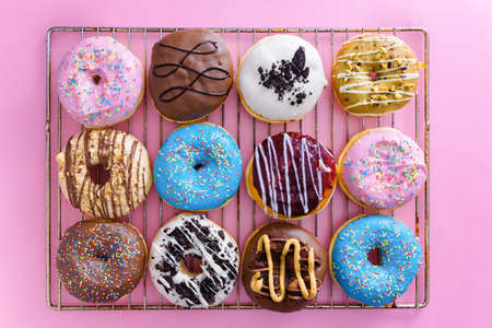 Overhead view of colorful donuts on top of pink background.の写真素材
