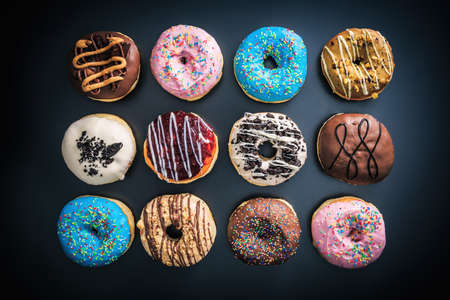 Top down view of various colorful donuts, on top of black background.の写真素材