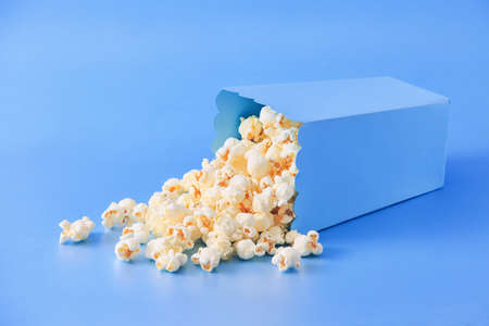 Popcorn in a blue bucket, isolated on top of blue background.の写真素材