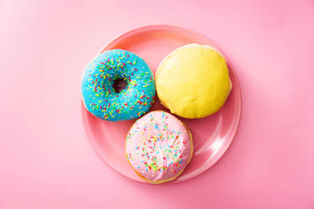 Top down view of served pink plate with colorful donuts, against pink background.の写真素材