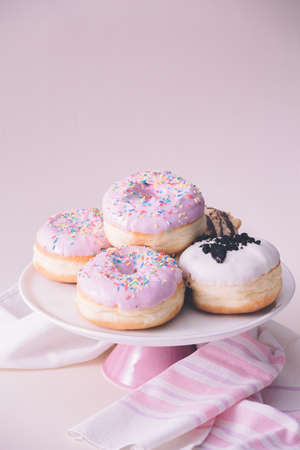 Several fresh donuts with pink glaze, on top of the pink plate, served on pink background.の写真素材
