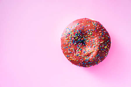 Overhead view of chocolate donut with sprinkles, on top of purple background, with available copy space.の写真素材